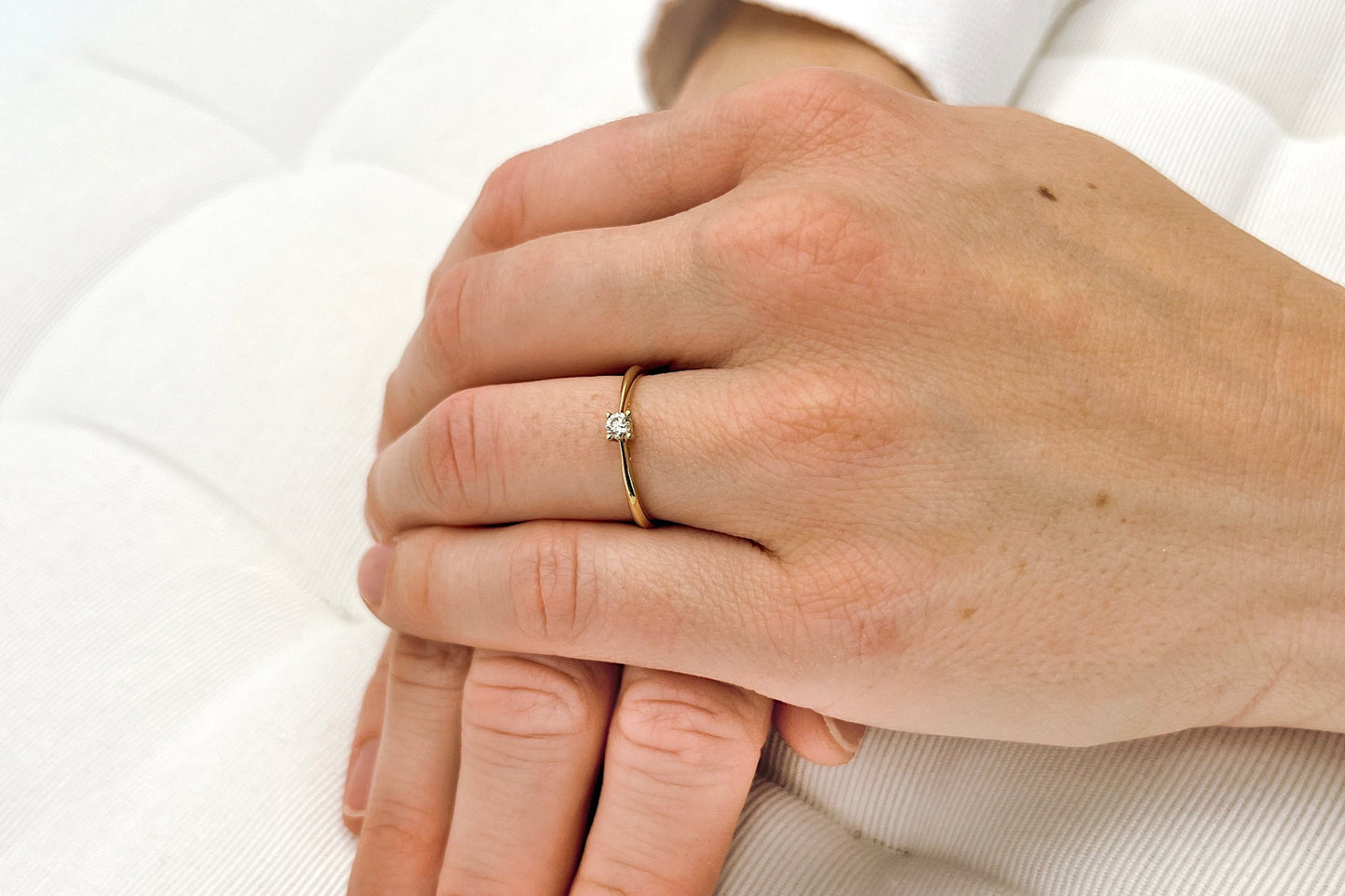 Ein Solitär Diamantring aus Gelbgold mit 0,1ct getragen an einer Frauenhand