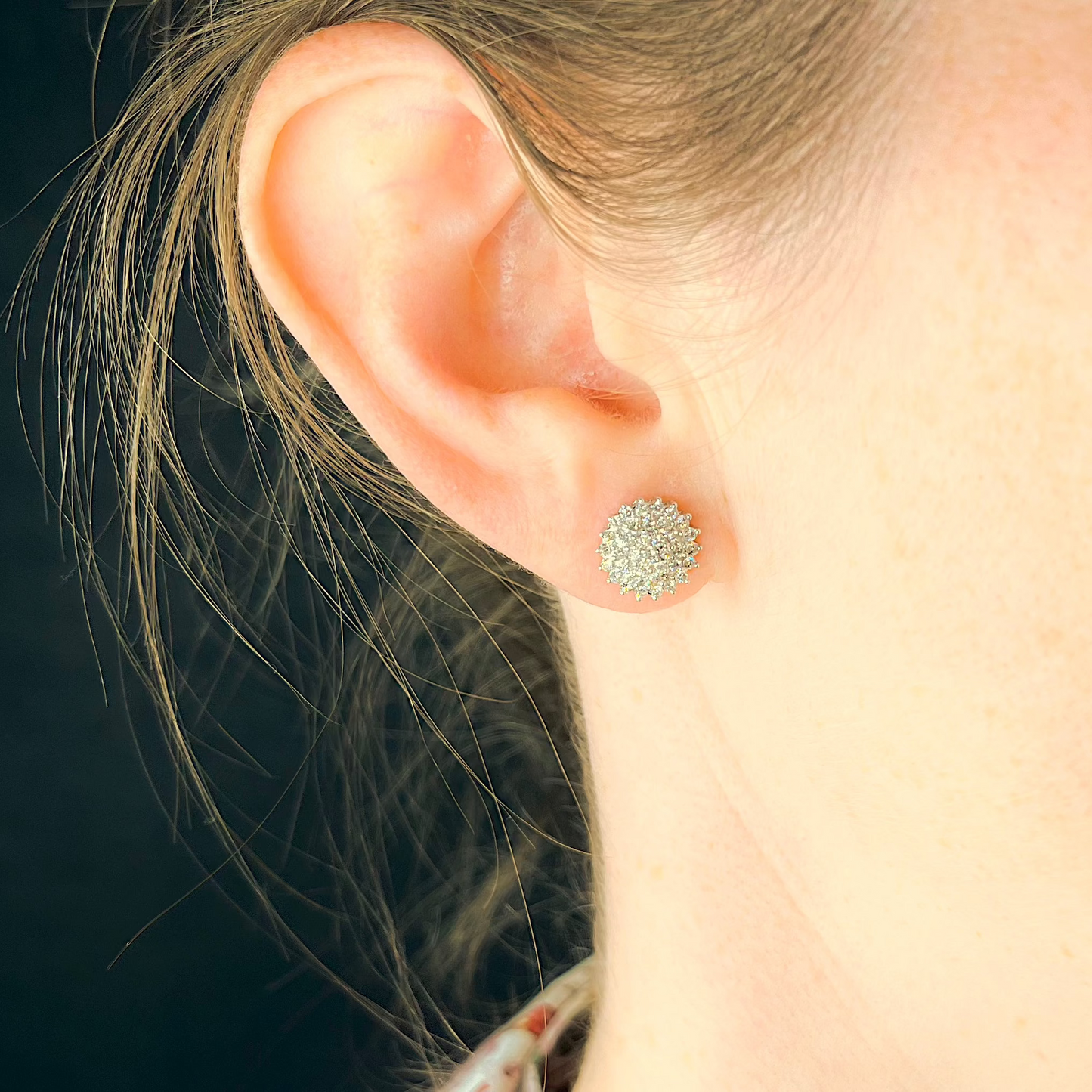 Große Diamantohrstecker aus Weißgold mit dicht gefassten Diamanten am Ohr getragen