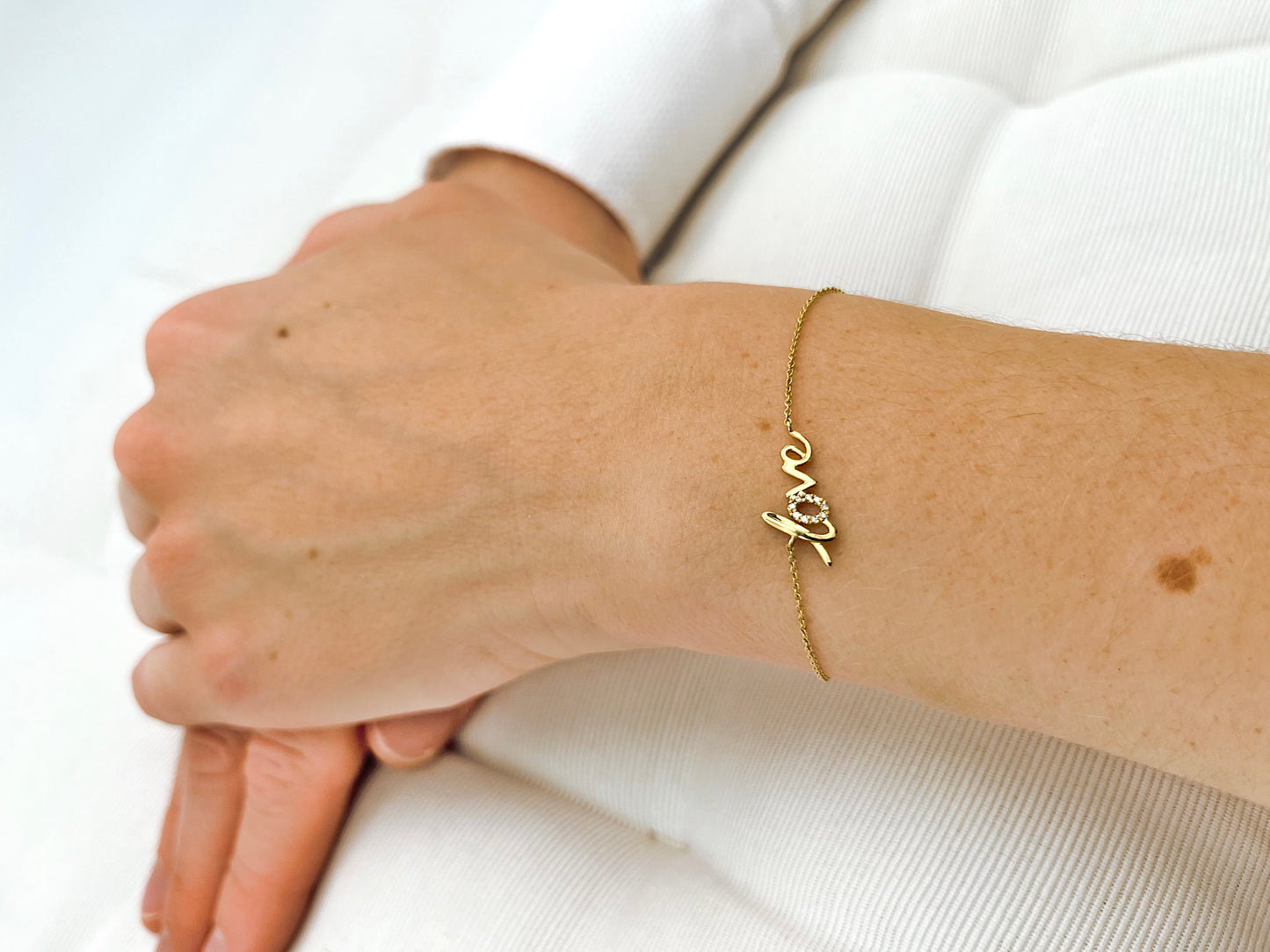 Armband mit "love" Schriftzug aus Gelbgold mit Diamanten besetzt am Arm getragen