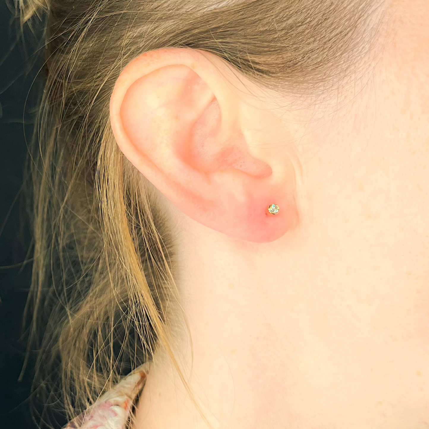 Ohrstecker aus Rotgold mit Solitärdiamant in Zargenfassung am Ohr getragen