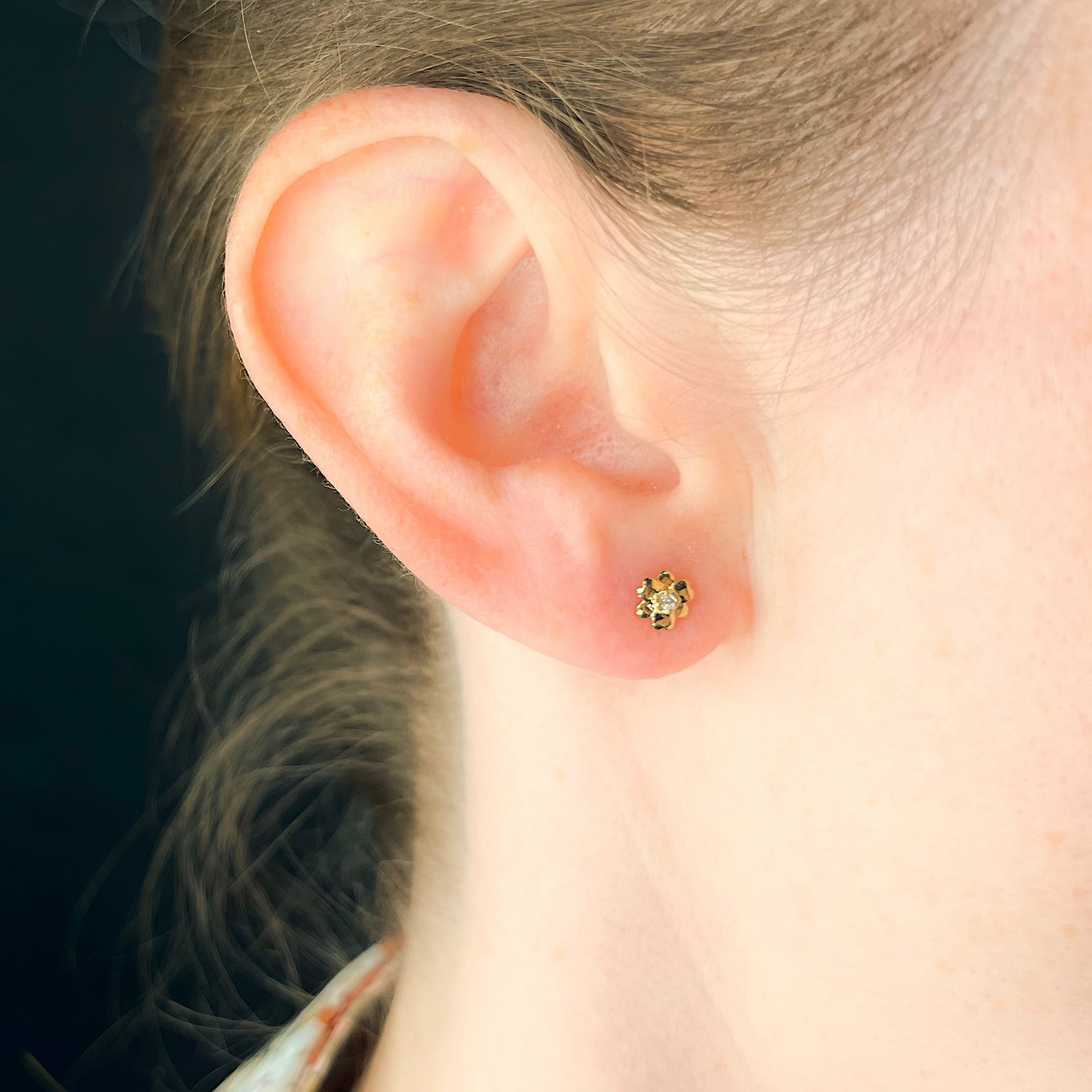 Ohrstecker in Blütenform aus Gelbgold mit Diamanten besetzt getragen am Ohr