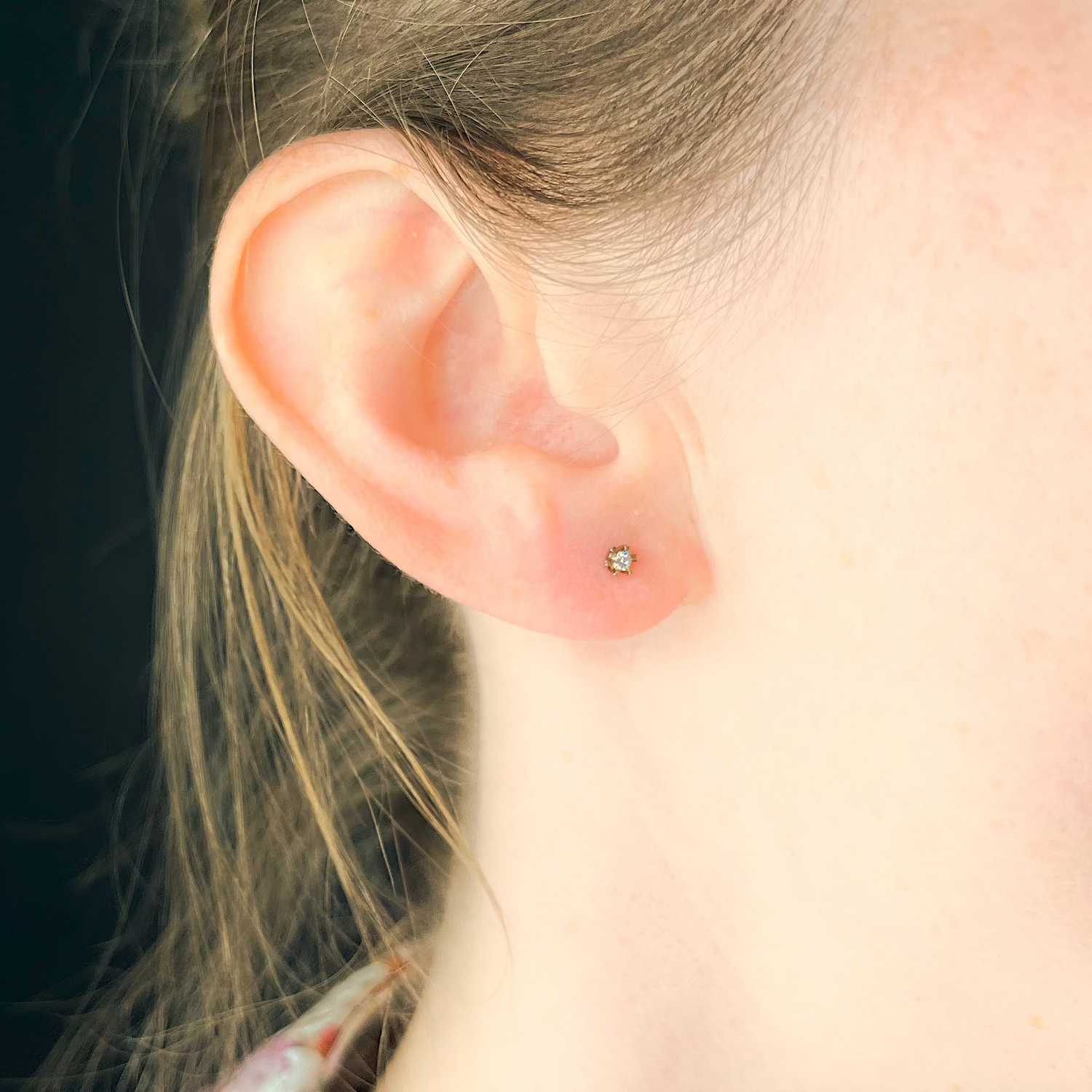 Kleine Diamantohrstecker aus Rotgold mit Krappenfassung getragen am Ohr